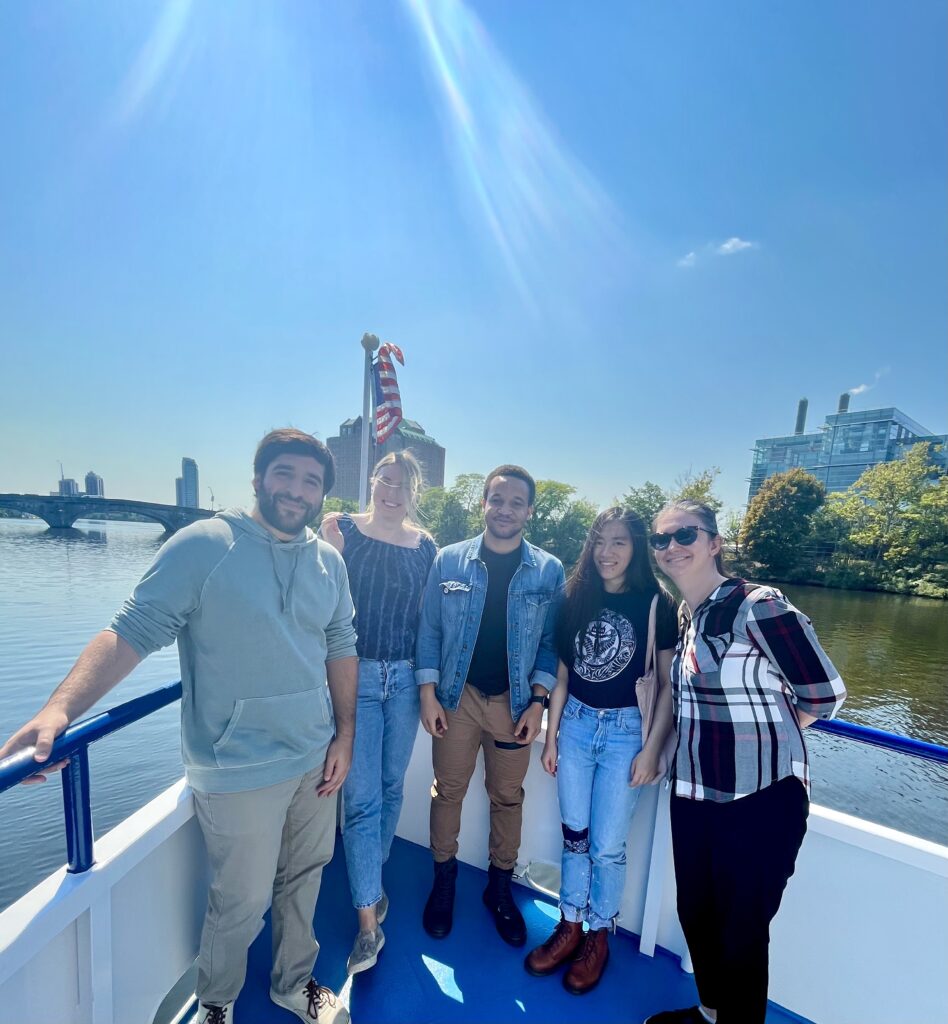 Five people standing on a boat deck in the sun.