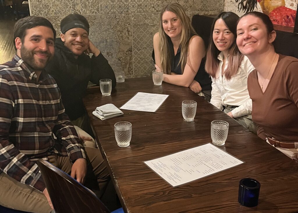 Five people sitting around a table and smiling for a photo